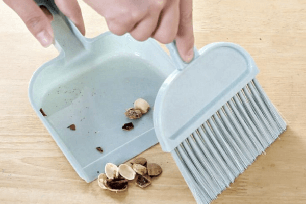 Pá coletando cascas de sementes e fezes durante a limpeza do terrário do hamster.